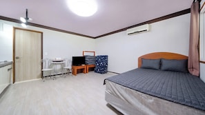 A bedroom with a bed, a desk with a computer, a chair, a TV, and an air conditioning unit. - Paju Gamaksan Sanchon Village Pension (Paju)