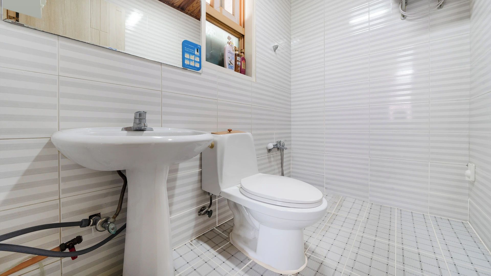 A bathroom with a white sink, toilet, and tiled walls.
