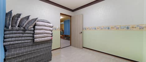 A hallway with a stack of mattresses, a door, and a tiled wall with a border.