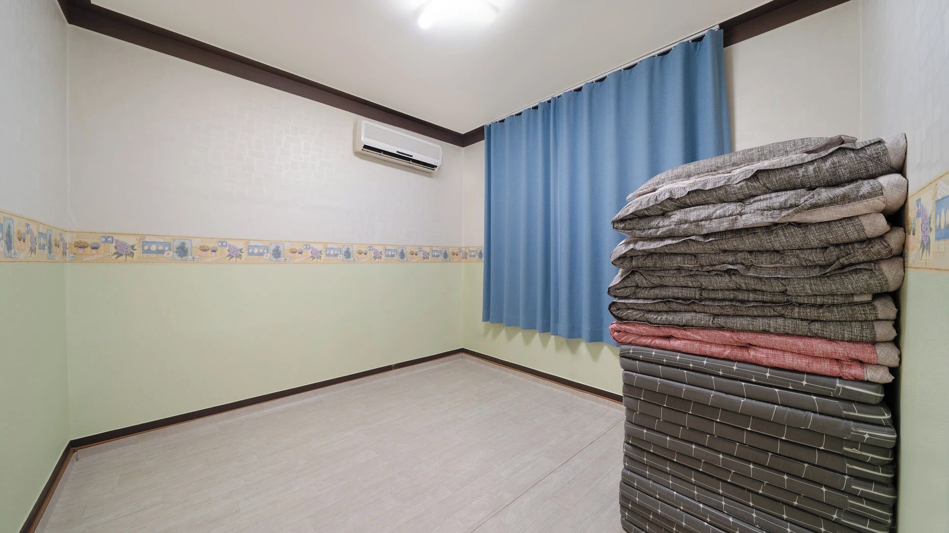 A room with a tiled floor, a blue curtain, and a stack of folded towels.
