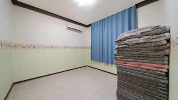 A room with a tiled floor, a blue curtain, and a stack of folded towels.