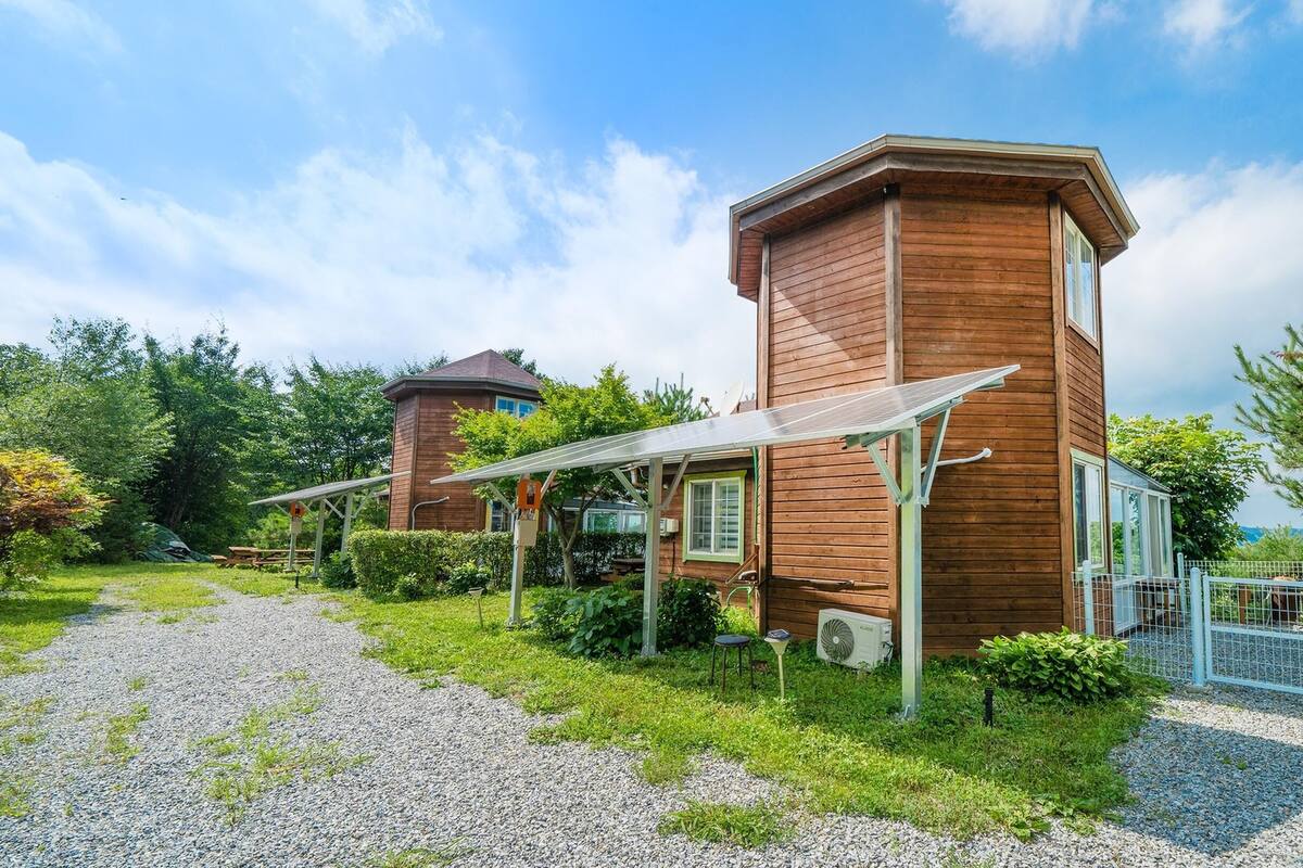 Ein zweigeschossiges Holzhaus mit Schotterauffahrt und einem eingezäunten Bereich.