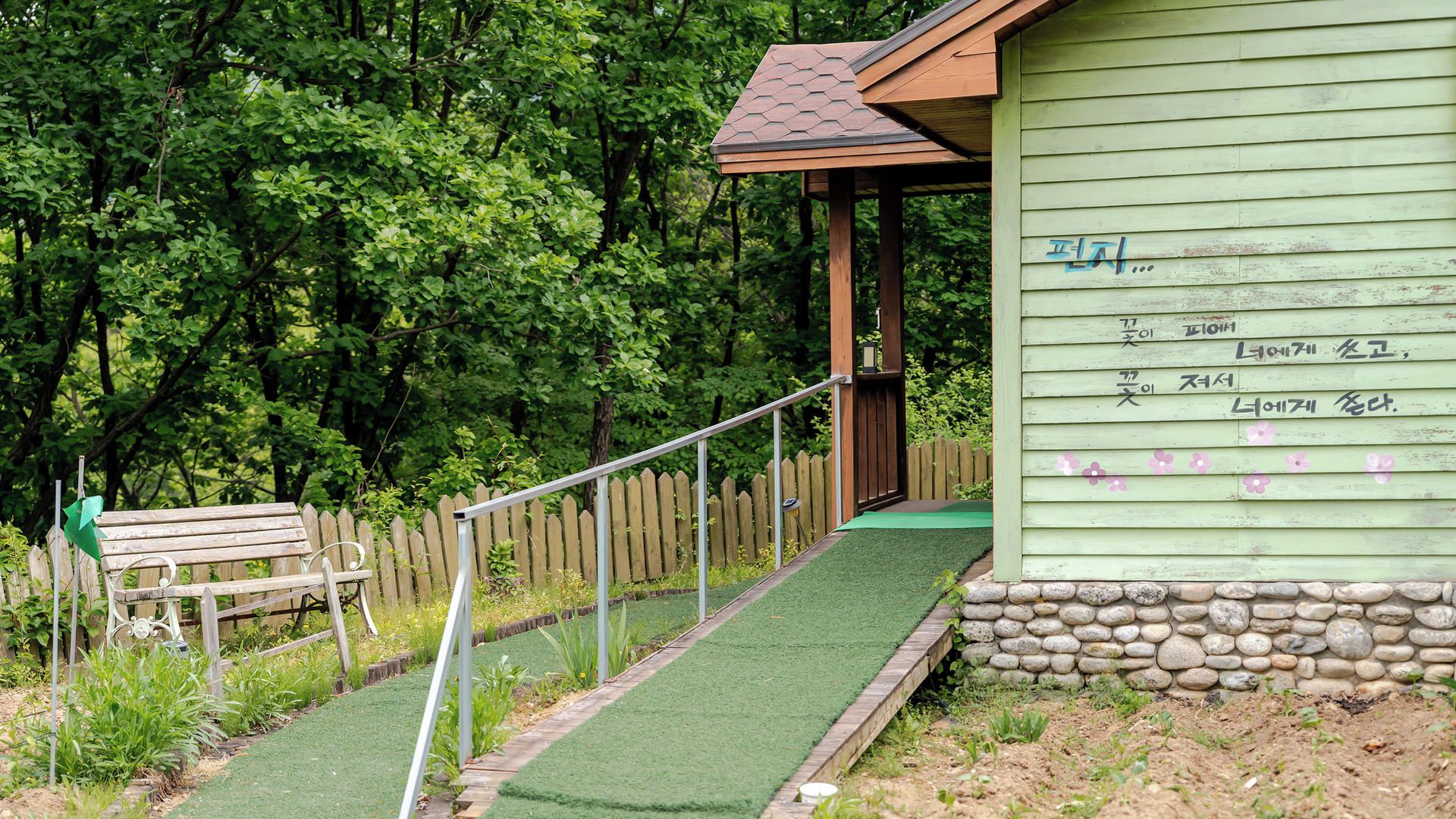 A wooden bench, a wooden fence, and a building with Korean text.