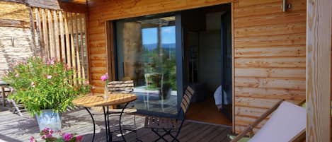 Una cabaña de madera con un porche, una mesa y un banco.