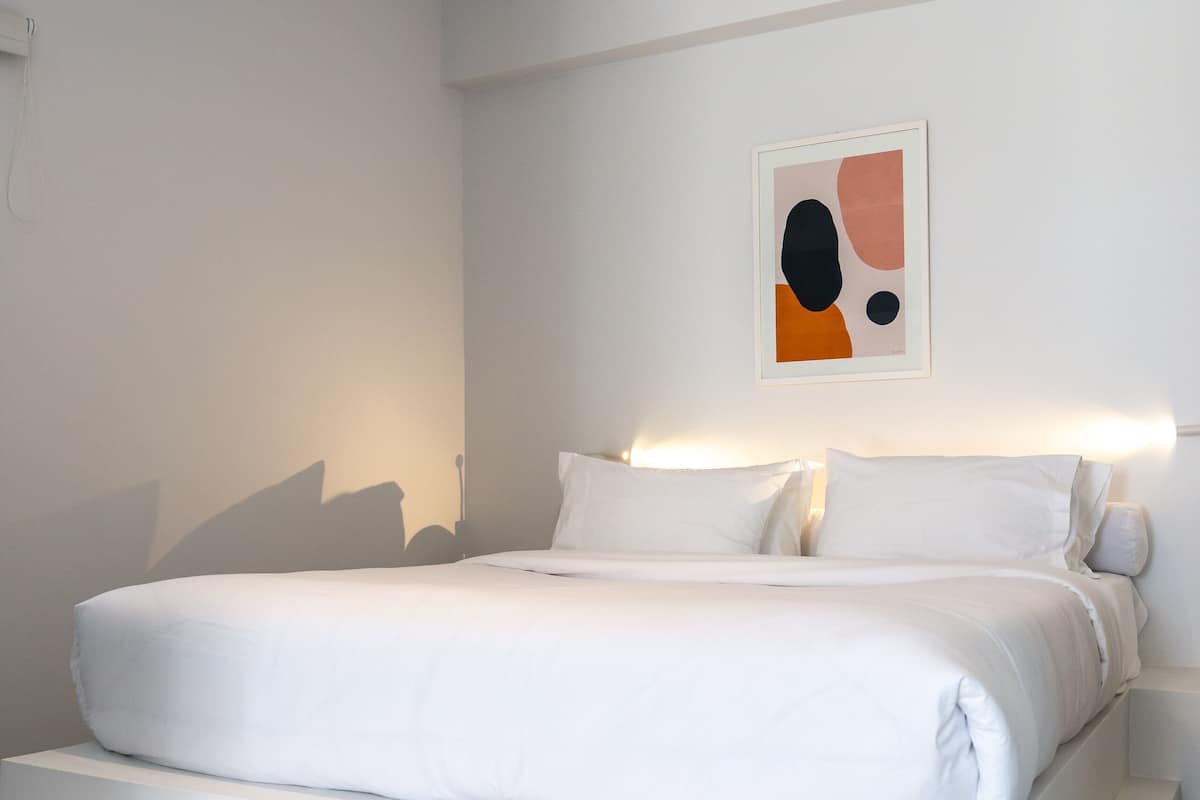 Een moderne hotelkamer met een groot bed, een nachtkastje en een abstract kunstwerk aan de muur.