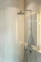 Ducha moderna con cabezal de ducha manual y controles incorporados a la pared.