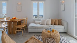 Een moderne woonkamer met een bank, eettafel en stoelen. Er is een groot raam met uitzicht op de stad.