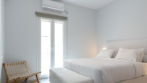 Een moderne slaapkamer met een groot bed, een houten stoel en een schuifdeur naar een balkon.