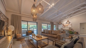 A spacious living room with a high ceiling, large windows, and a cozy seating area. - Ubuntu Luxury Villa, with private pool, 3-and-suite bedrooms, near Kruger Park (Hoedspruit)