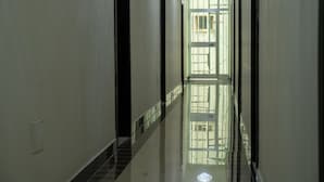 Un pasillo largo y estrecho con piso reflectante, que conduce a una puerta con ventanas de celosía.