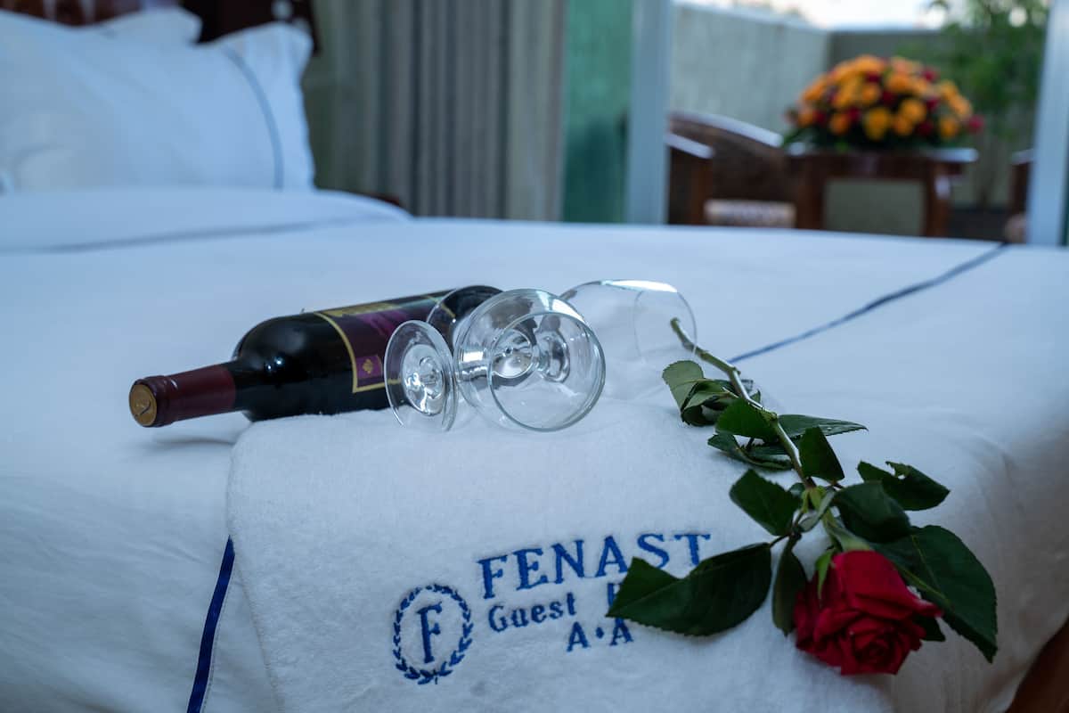 A bed with a towel that has the logo "FENAST" and "Guest A.A" on it.