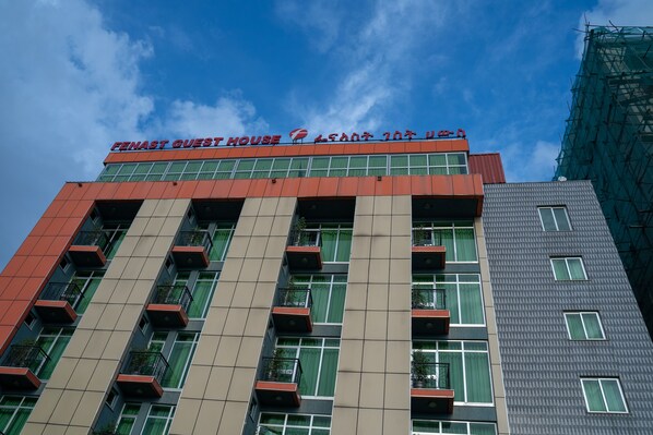 Ein Hotel mit moderner Fassade, mehreren Balkonen und blauem Himmel.