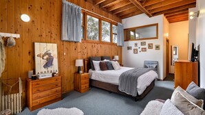 Ein gemütliches Schlafzimmer mit Holzwänden, einem großen Bett, einer Kommode und einem Spiegel.