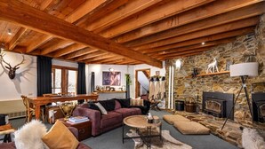 Ein gemütliches Wohnzimmer mit Kamin aus Stein, Holzbalken und rustikalen Einrichtungsgegenständen.