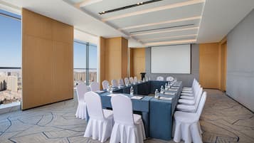 A conference room with a long table, white chairs, and a city view.