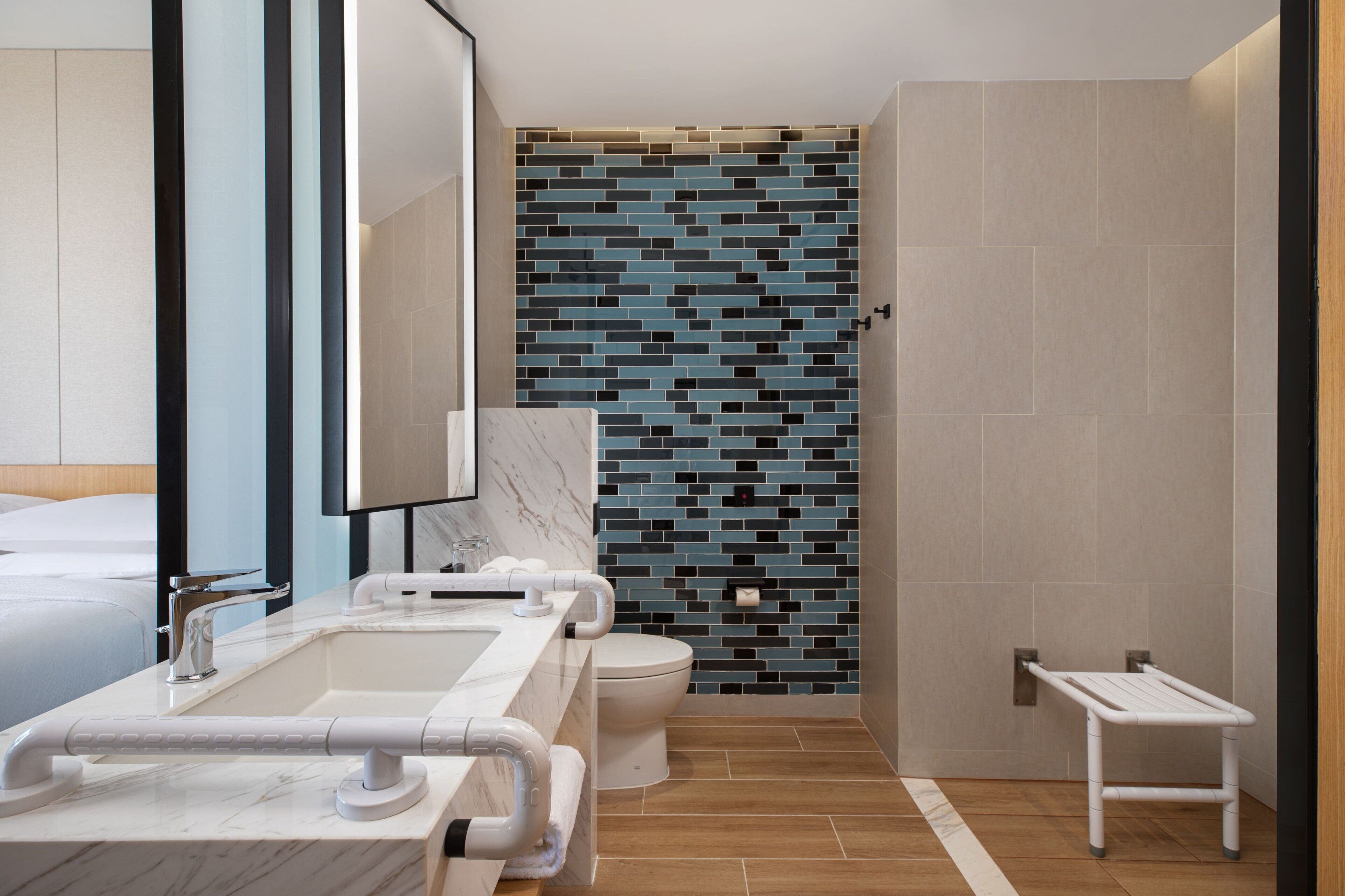 A modern bathroom with a marble sink, a toilet, and a shower area.