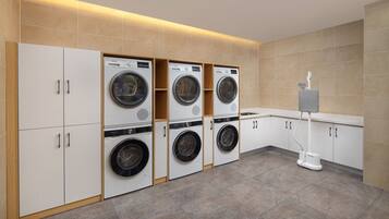 A modern laundry room with four stacked washing machines and a water fountain.