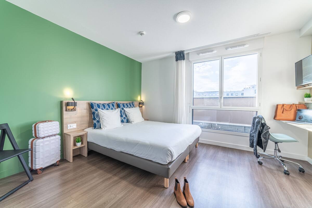 A modern bedroom with a bed, bedside table, and a window.