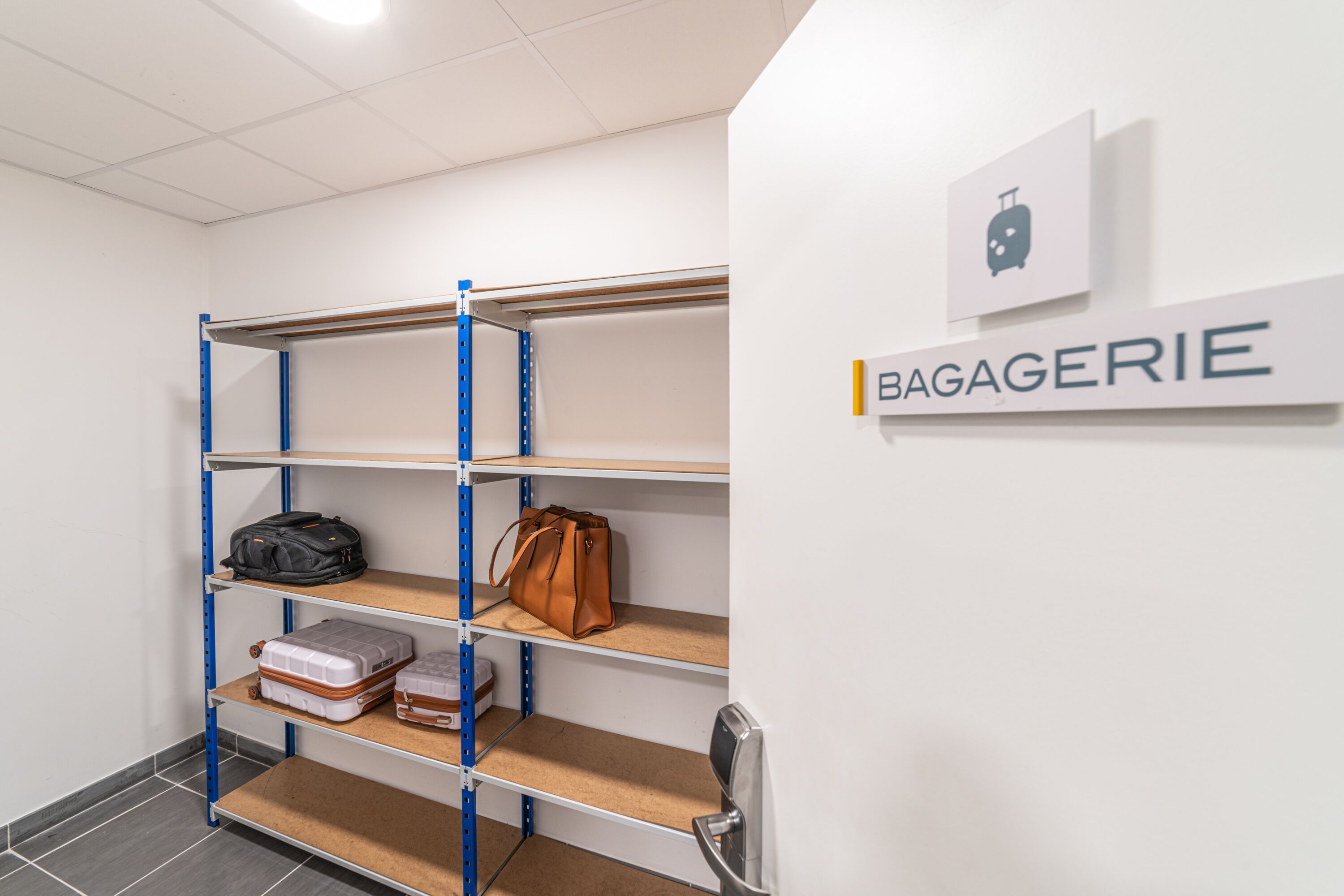 Un espace de stockage équipé d’étagères métalliques, dont certaines contiennent des sacs et des valises.