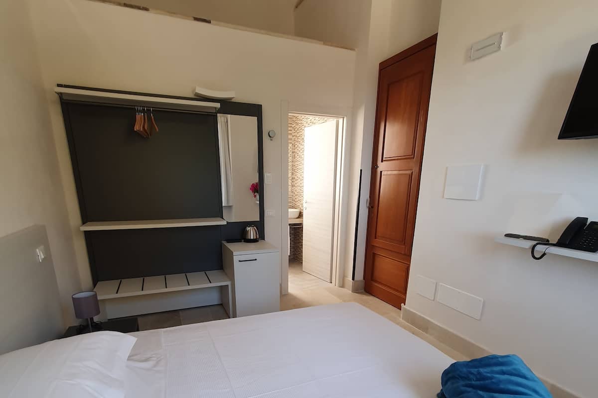 Una habitación de hotel con cama, escritorio, armario y televisión.