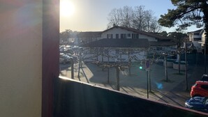 Un quartier résidentiel avec des voitures garées, un ciel dégagé et un bâtiment doté d’un toit en tuiles.