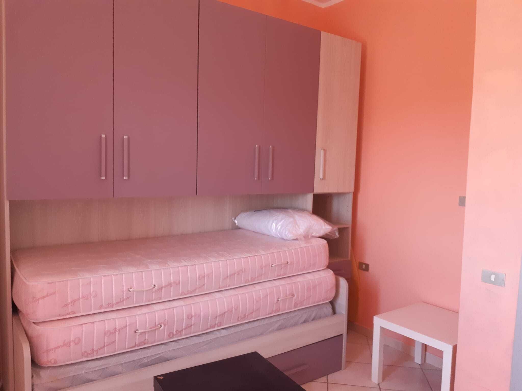 A bedroom with a bed, a small table, and a wardrobe.