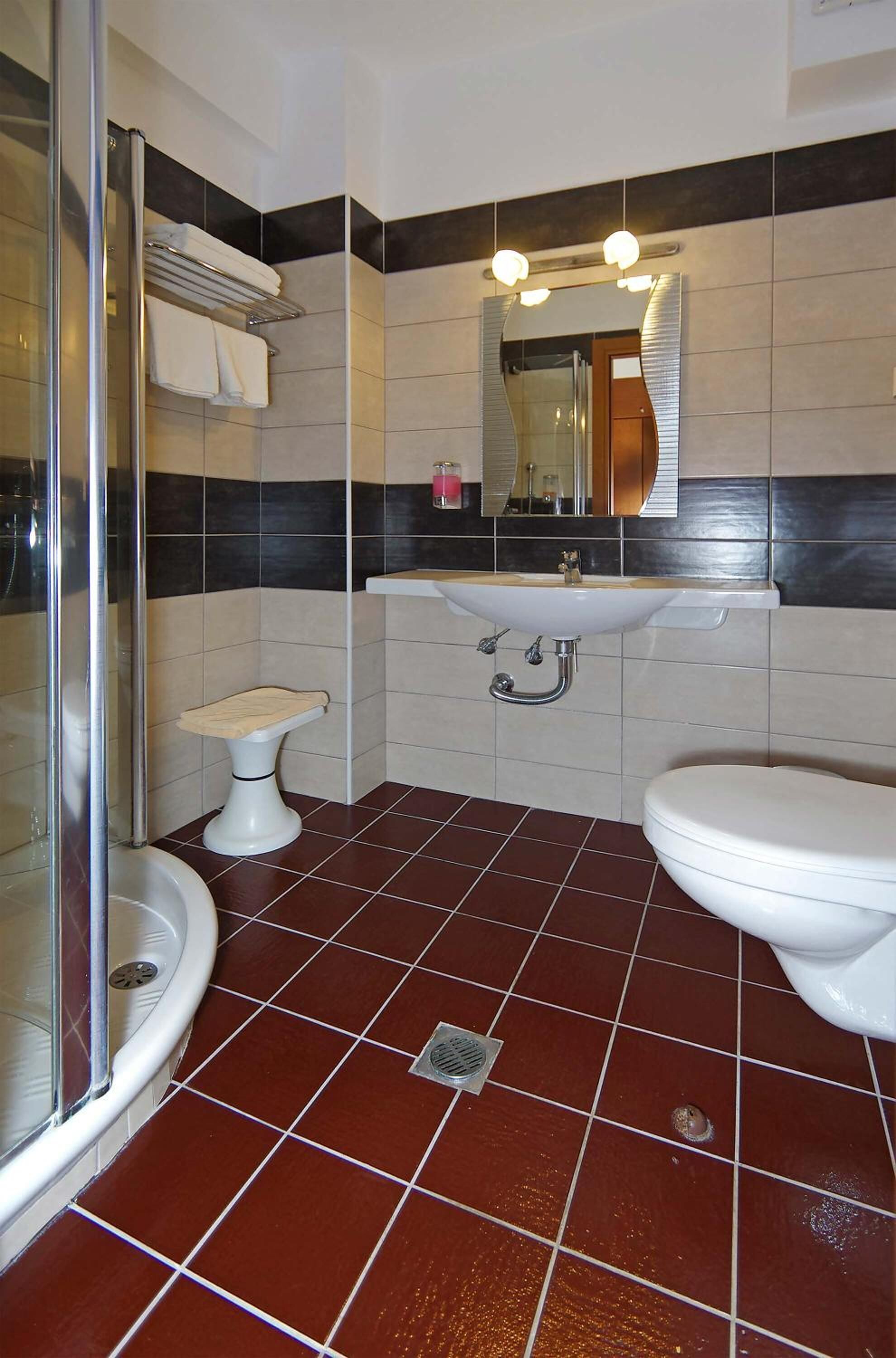 Ein Badezimmer mit Dusche, Toilette, Waschbecken und einem Spiegel über dem Waschbecken.