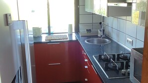 Eine kleine Küche mit Kühlschrank, Herd, Spüle und Schränken.