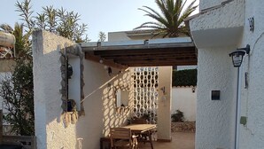 Ein Schwimmbad mit Holzterrasse, einer überdachten Terrasse und einer weißen Wand mit einer Zierkolumne.