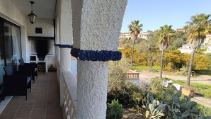 A balcony with a seating area, a fireplace, and a view of a garden with palm trees and other vegetation. - Majorcan charm, with private pool and 100m from the beach. (CALA ROMANTICA)
