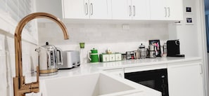 A modern kitchen with white cabinets, a stainless steel kettle, a coffee maker, and a dishwasher. - 270 On Church - Mudgee's Hidden Gem (MUDGEE)
