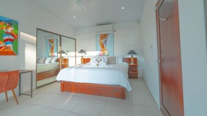 A modern bedroom with a large bed, a desk, and a chair. There are two bedside tables with lamps.