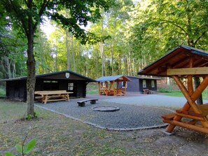Un camping con cabañas de madera, mesas de picnic y un pozo para fogatas.