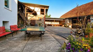 An outdoor area with a ping pong table, red benches, and a stone wall.