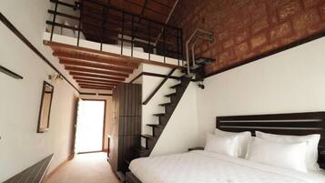 Ein Schlafzimmer mit einem großen Bett, einer Holztreppe und Blick ins Freie.