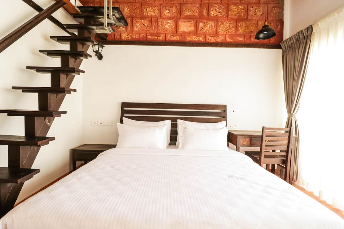 Quarto com cama de madeira, mesa de cabeceira, uma cadeira e escada.