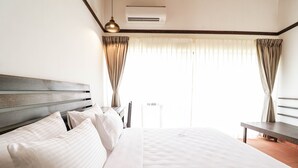 Una habitación de hotel con una cama grande, una mesita de noche, una lámpara y una ventana con cortinas.