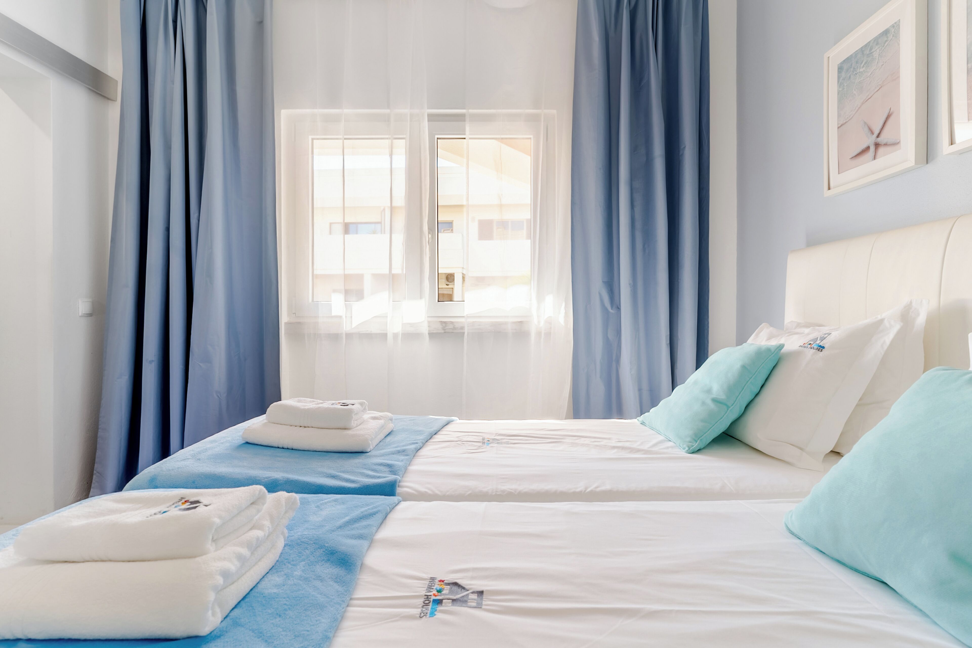 Een hotelkamer met twee bedden, een groot raam en uitzicht op gebouwen.