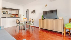 A compact living space with a dining area, a kitchen, and a TV mounted on a wooden cabinet. - Ocean View • Walk to Beach • Pool • Lagos • 64 (Lagos)
