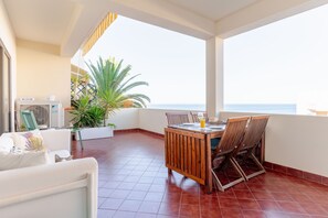 A terrace with a wooden table and chairs, a white sofa, and a potted plant. - Ocean View • Walk to Beach • Pool • Lagos • 64 (Lagos)