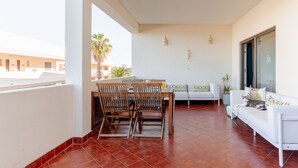 A balcony with a dining table, chairs, a sofa, and a potted plant. - Ocean View • Walk to Beach • Pool • Lagos • 64 (Lagos)