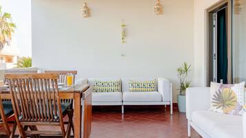 A living room with a white sofa, wooden chairs, a dining table, and a decorative wall with two hanging lanterns.