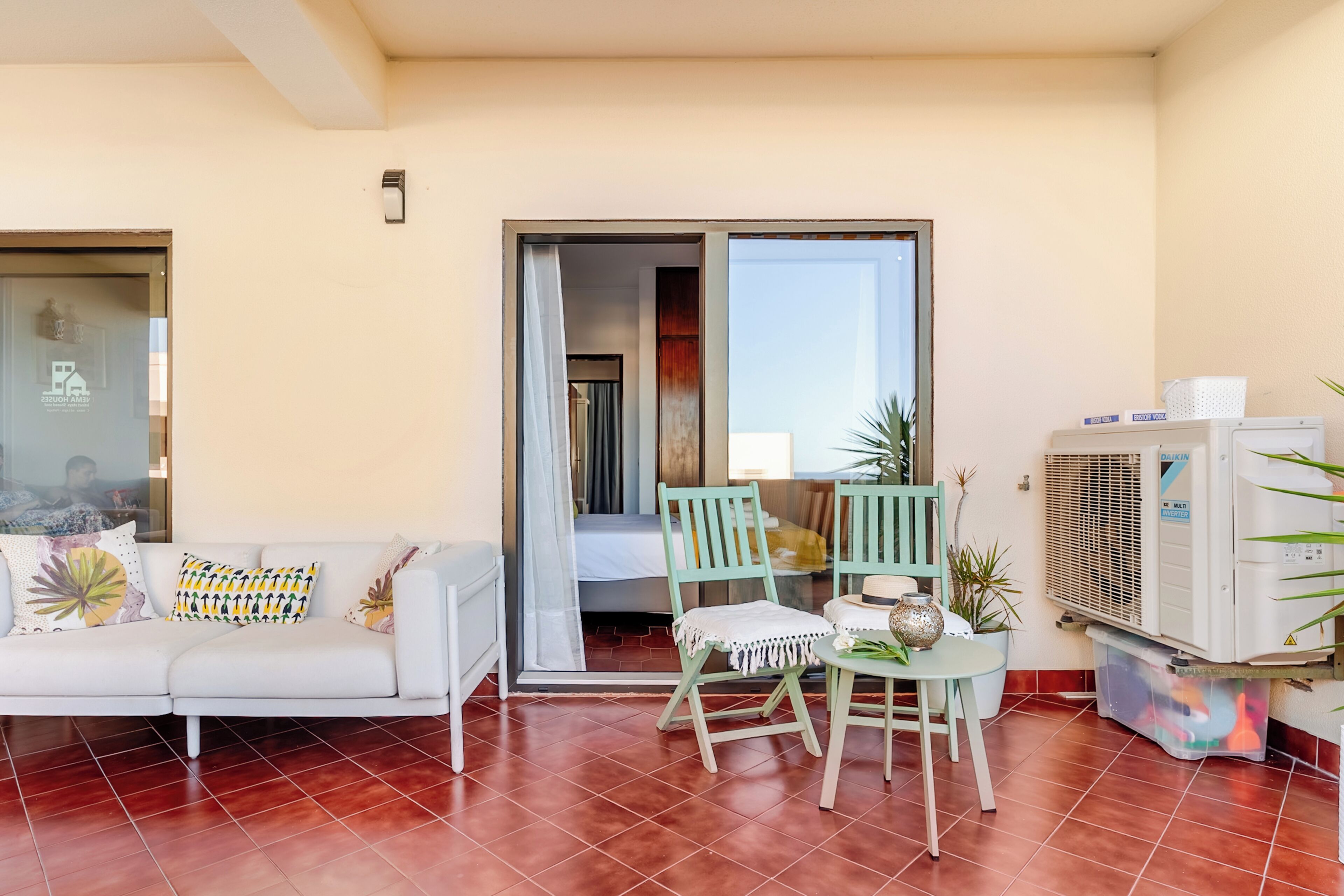 Un salon comprenant un canapé, des fauteuils, une petite table et un appareil de climatisation.