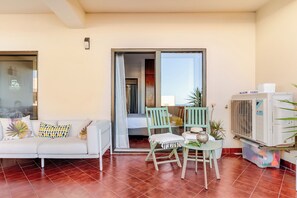 A living room with a sofa, chairs, a small table, and an air conditioning unit. - Ocean View • Walk to Beach • Pool • Lagos • 64 (Lagos)