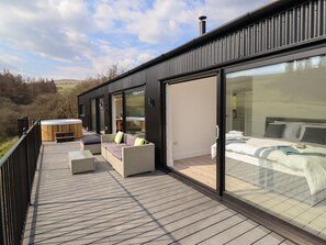 Una terraza moderna al aire libre con un jacuzzi, zona de estar y un dormitorio con cerramiento de vidrio.