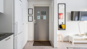 A modern kitchen with white cabinets, a black countertop, and a gray door with various notices.