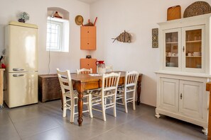 A kitchen with a dining table, chairs, a refrigerator, a cabinet, and a window.