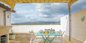 A terrace with a table set for breakfast, white chairs, and a view of the countryside.