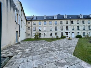 Une cour avec un chemin de pierre menant à un bâtiment doté de nombreuses fenêtres et de balcons.
