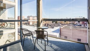 A balcony with two wicker chairs and a small round table, overlooking a parking area and buildings. - Hiisi Homes Nokia (Nokia)